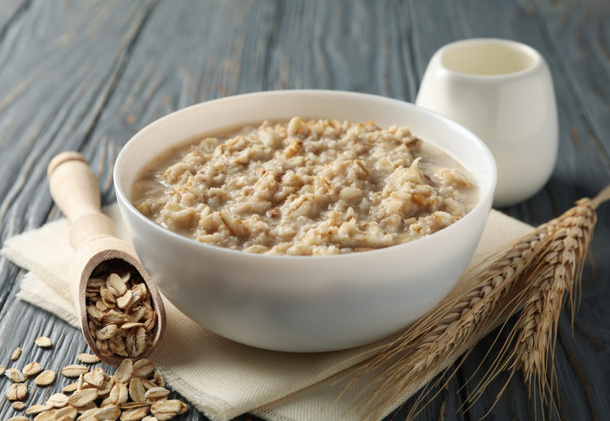 Composition with oatmeal porridge on wooden background. Cooking breakfast
